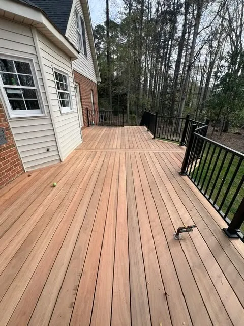 A wooden deck with a railing surrounded by trees.