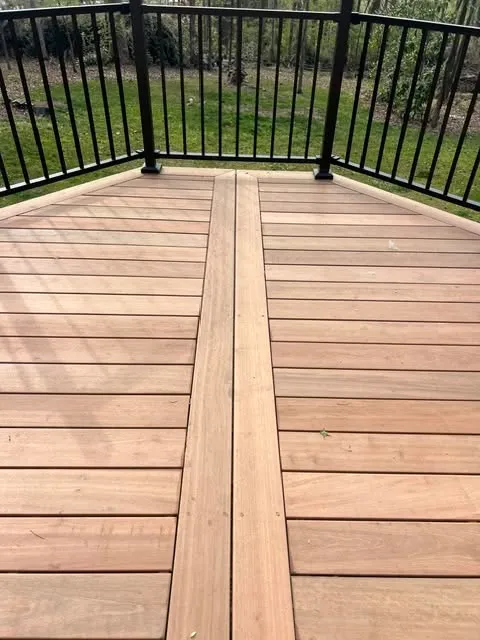 A close-up view of wooden decking on a balcony with black railing.
